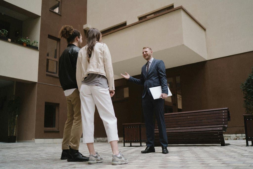 Un agente immobiliare parla con una coppia nel cortile di un palazzo